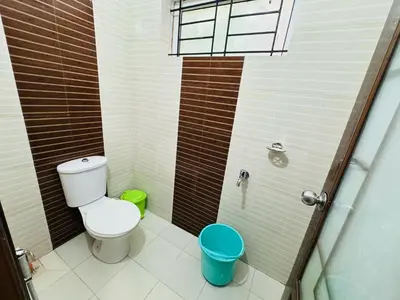 a small bathroom with a toilet and a shower at Anandha Vibes in Guruvāyūr