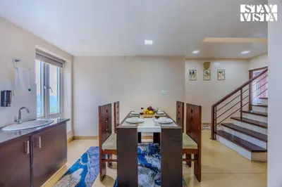 a kitchen with a table with a sink and a staircase at Mistydawn Villas By Sunset Valley by VEO - Part of StayVista in Ooty