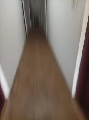 a hallway with a wooden floor and an open door at chenniyappa lodge in Chennimalai