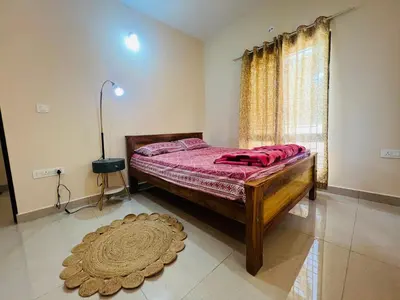 a bedroom with a bed and a window and a rug at Green Heaven Mysore Homestay in Mysore