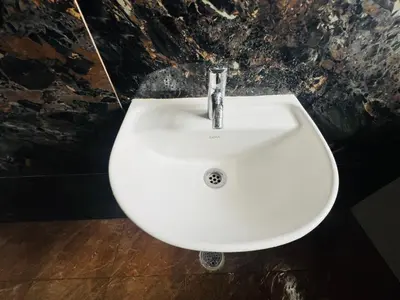 a white sink in a bathroom with a stone wall at Green Heaven Mysore Homestay in Mysore