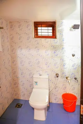 a bathroom with a white toilet and a window at Orange Villa -3 AC Rooms Near Airport in Ernakulam