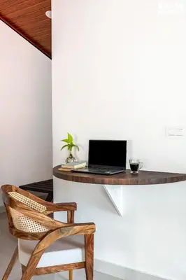 a desk with a laptop on a wall with a chair at StayVista at Hermitage 4BR - Boutique Stay - Relax in Nature in Irpu