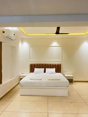 a bedroom with a white bed with a ceiling at Aagneyam Grand Resort in Kozhikode
