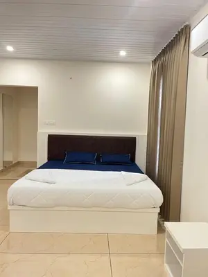 a bedroom with a large white bed with blue pillows at Aagneyam Grand Resort in Kozhikode