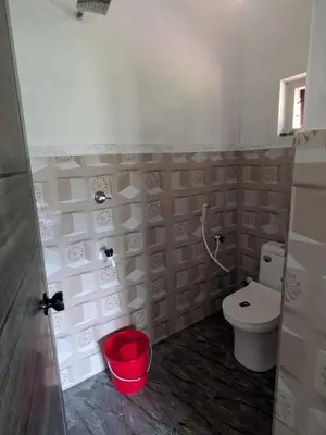 a bathroom with a toilet and a red bucket at Silent Stays in Kelakam