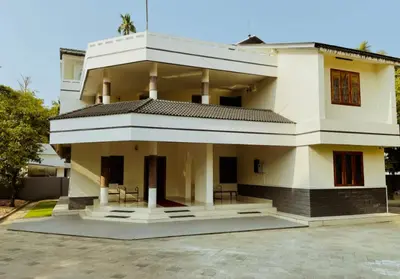 a large white building with chairs in front of it at Upavan Villa-Two KM From Aluva Metro Station in Alwaye
