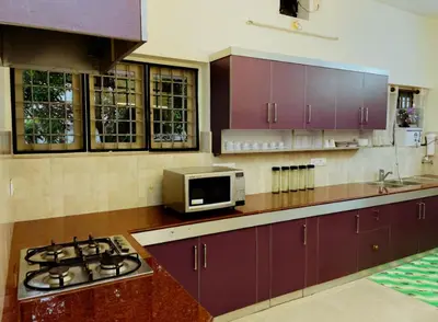 a kitchen with purple cabinets and a stove and a microwave at Upavan Villa-Two KM From Aluva Metro Station in Alwaye