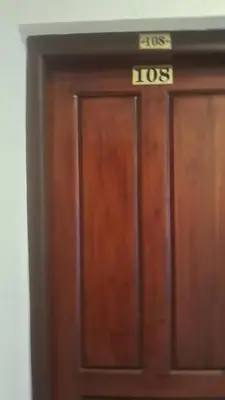 a wooden door with a sign on top of it at Hill palace Inn in Periya