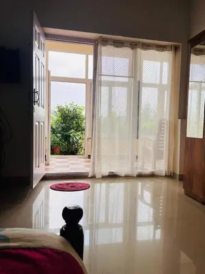 a bedroom with a dog sitting on the floor in front of a door at Nvoyages Plantataion Stay Coorg in Madikeri