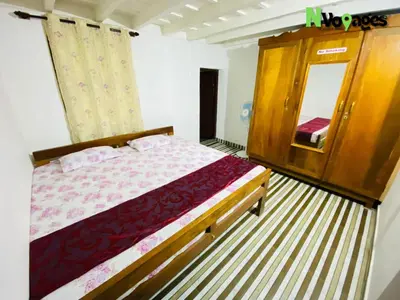 a bedroom with a bed and a dresser and a mirror at Nvoyages Plantataion Stay Coorg in Madikeri