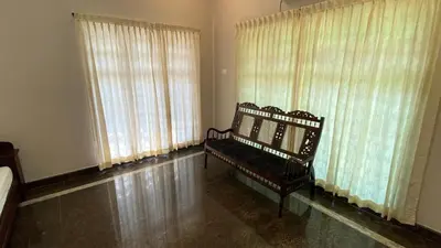 a room with a bench in front of windows at Abida Mansion 4BHK Near MCP Convention Centre Irinjalakuda in Irinjālakuda