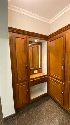 a closet with wooden cabinets and a mirror at Abida Mansion 4BHK Near MCP Convention Centre Irinjalakuda in Irinjālakuda
