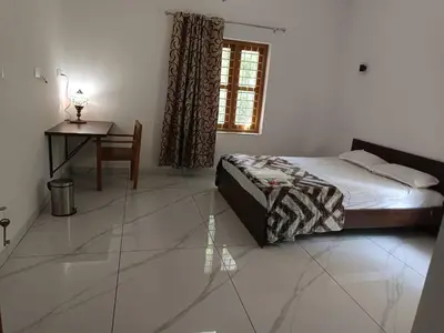 a bedroom with a bed and a table and a desk at Aathira Agri Homes in Trichūr