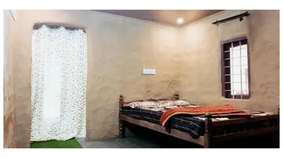 a bedroom with a bed and a window with a curtain at Mud bees resort in Kanthalloor