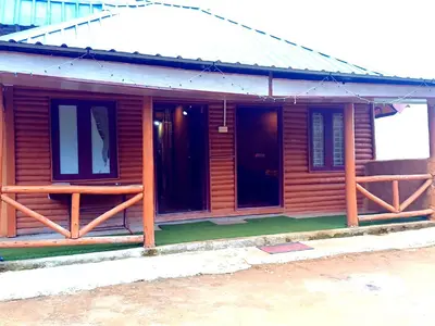 a wooden cabin with a porch and two windows at Mud bees resort in Kanthalloor