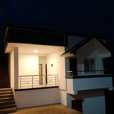 a small white house with a balcony at night at Mithra Cottages Individual Room's with Balcony in Ooty