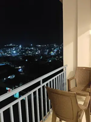 a balcony with a view of a city at night at Mithra Cottages Individual Room's with Balcony in Ooty