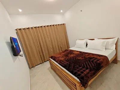 a bedroom with a bed with a curtain and a tv at Mithra Cottages Individual Room's with Balcony in Ooty