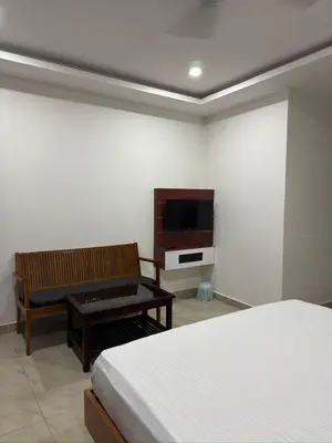 a bedroom with a bed and a table and a tv at RV Tourist Home in Ponnāni