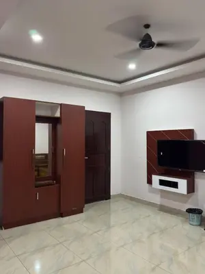 a living room with wooden cabinets and a flat screen tv at RV Tourist Home in Ponnāni