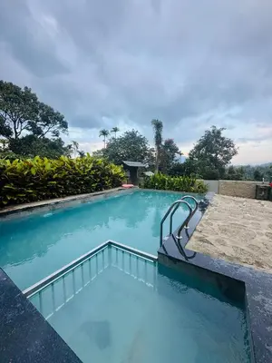 a swimming pool with blue water in a resort at Hill Brown Resort in Kalpetta
