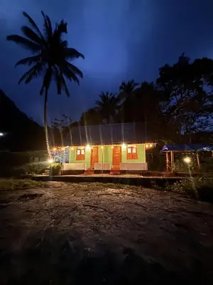 a small house with a palm tree at night at ViAN Mistyrocks in Mamalakandam