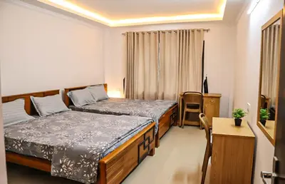 a small bedroom with two beds and a desk at Highland Residency in Attappādi