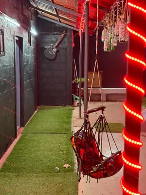 a hammock hanging from a pole in a room with grass at Highland Residency in Attappādi