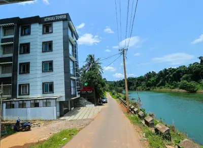 a building on the side of a road next to a river at Atholi Residency in Mukkam