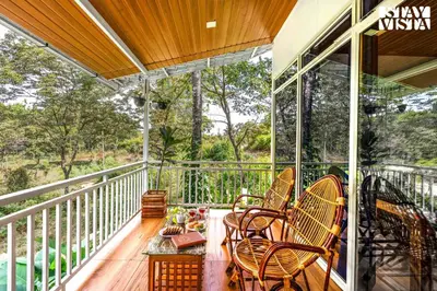a porch with chairs and a table on a balcony at StayVista at Aradhya Villa with Infinity Pool, Lawn in Wayanad