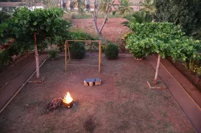 a fire in the middle of a garden with trees at Anava Farms in Shrīrangapattana