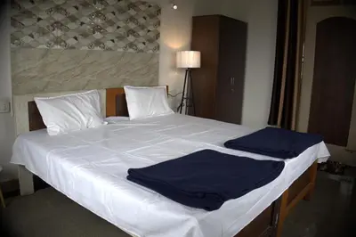 a large white bed with blue sheets and pillows at Anava Farms in Shrīrangapattana