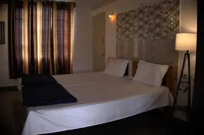 a bedroom with a bed with white sheets and pillows at Anava Farms in Shrīrangapattana