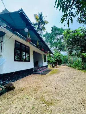 a white house with a blue roof and a yard at rivers edge homestay in Viripara