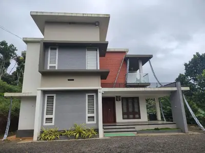 a white house with a red roof at Savisos home in Padinjarathara