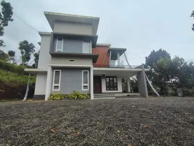 a large white house with a driveway in front of it at Savisos home in Padinjarathara
