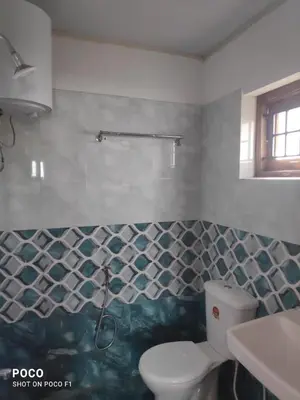 a bathroom with a toilet and a tiled wall at Lush Green View Cottage 3BH in Ooty