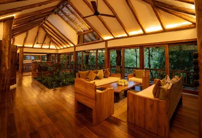 a living room with wooden furniture and windows at Avana Holiday Experiences,Wayanad in Kalpetta