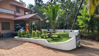 a garden with a picnic table in front of a house at Dreamland kizhunna beach homestay in Kannur