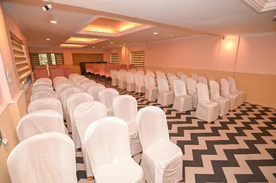 a room with rows of white chairs in a conference room at Hotel Vivek in Coonoor