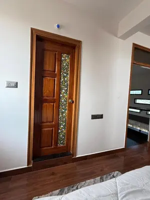 a bedroom with a wooden door and a window at Shan Home Stay in Mysore