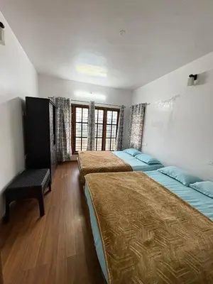 a bedroom with three beds and a bench in it at Sathya Holidays Evermist Stay in Ooty