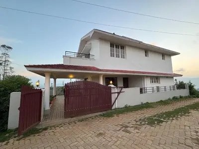 a white house with a red fence in front of it at Sathya Holidays Evermist Stay in Ooty