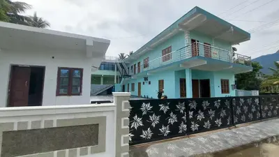 a blue and white house with a fence at Carmel Cottage in Marayoor