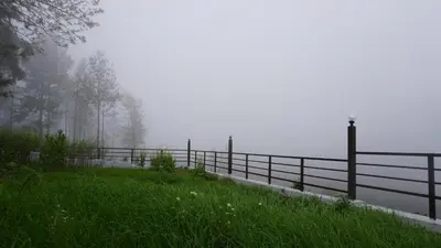 a fence on the side of a field in the fog at Luxurious Private Vantage Villa - Kotagiri in Kotagiri