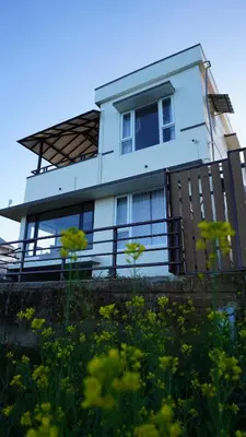 a white house with a fence and a field of flowers at Luxurious Private Vantage Villa - Kotagiri in Kotagiri