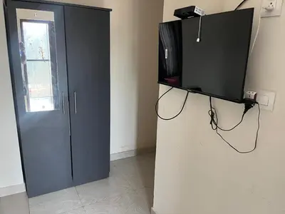 a black cabinet with a television on a wall at Sparsha rooms in Kaniyāmbetta