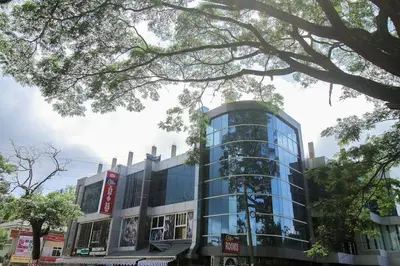 a large glass building with a sign on it at Sparsha rooms in Kaniyāmbetta