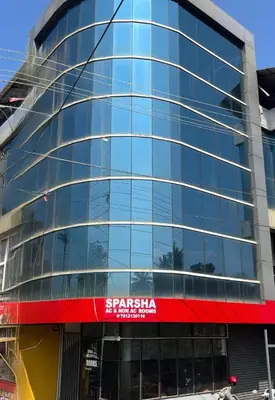 a large glass building with a sign on it at Sparsha rooms in Kaniyāmbetta